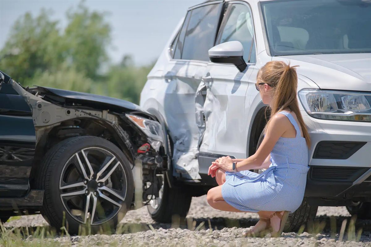 Woman inspecting damage to a white SUV
